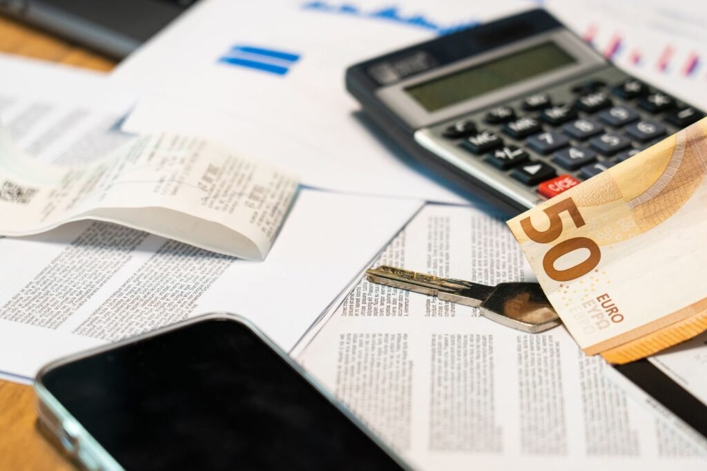 Finansiniai dokumentai, skaičiuotuvas ir euro banknotas ant stalo