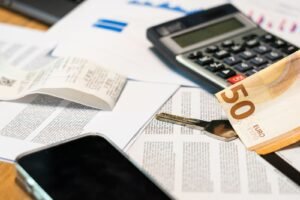 Finansiniai dokumentai, skaičiuotuvas ir euro banknotas ant stalo